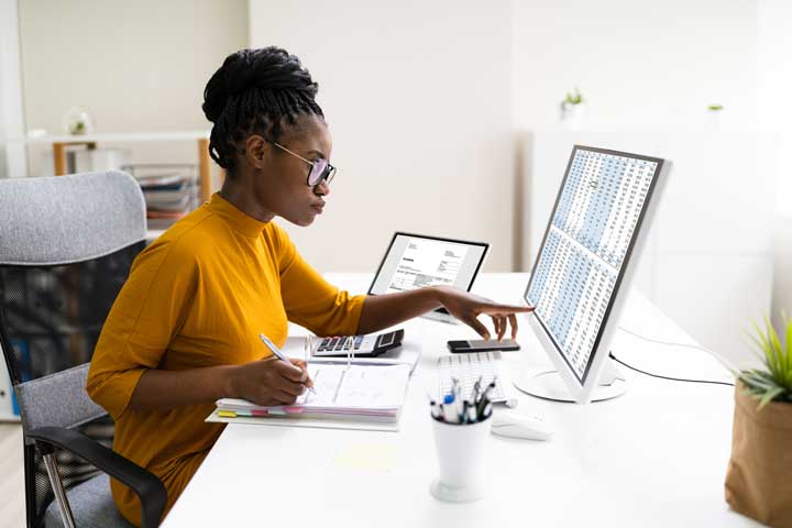 Woman reviewing spreadsheet on large computer screen