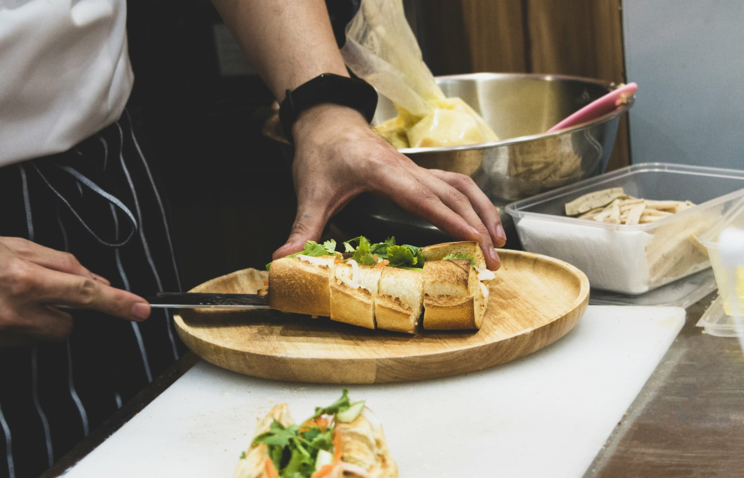Man slicing open baguette sandwich in a restaurant