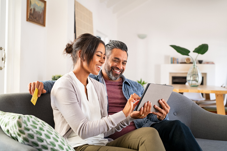 Couple using a tablet on a sofa. Don't forget that the deadline for topping up NI contributions has been extended again to 5 April 2025