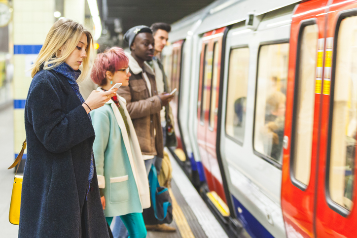 Women using phone wait for train