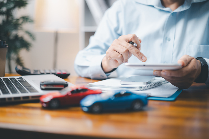 Man works on computer with toy cars on desk