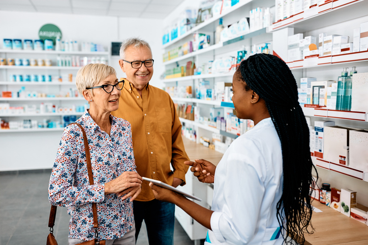 Senior couple talking to black female pharmacist in pharmacy