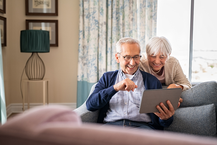 Old man using computer with help of his wife
