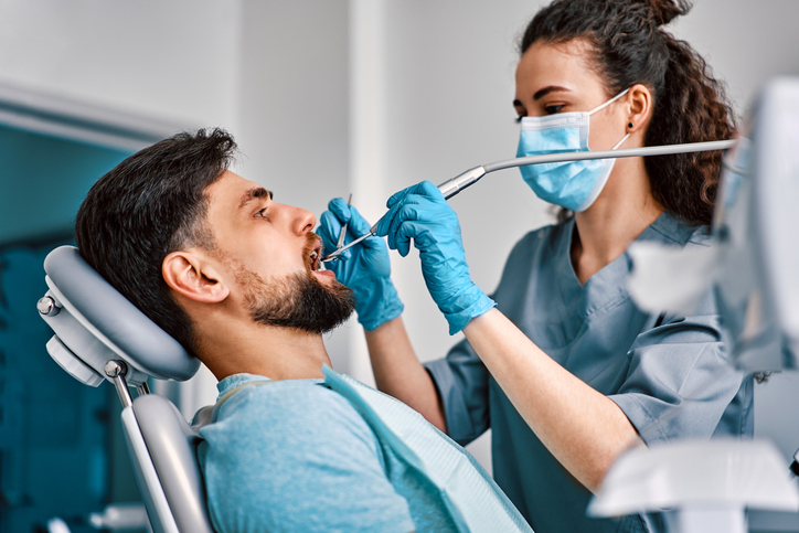 Dentistry, medicine. A female dentist in a mask treats a patient's teeth.